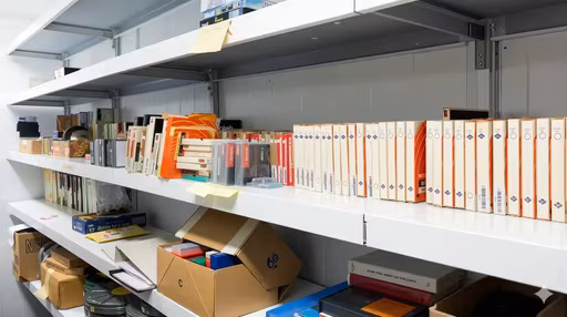 Arkistohylly täynnä nauhakoteloita